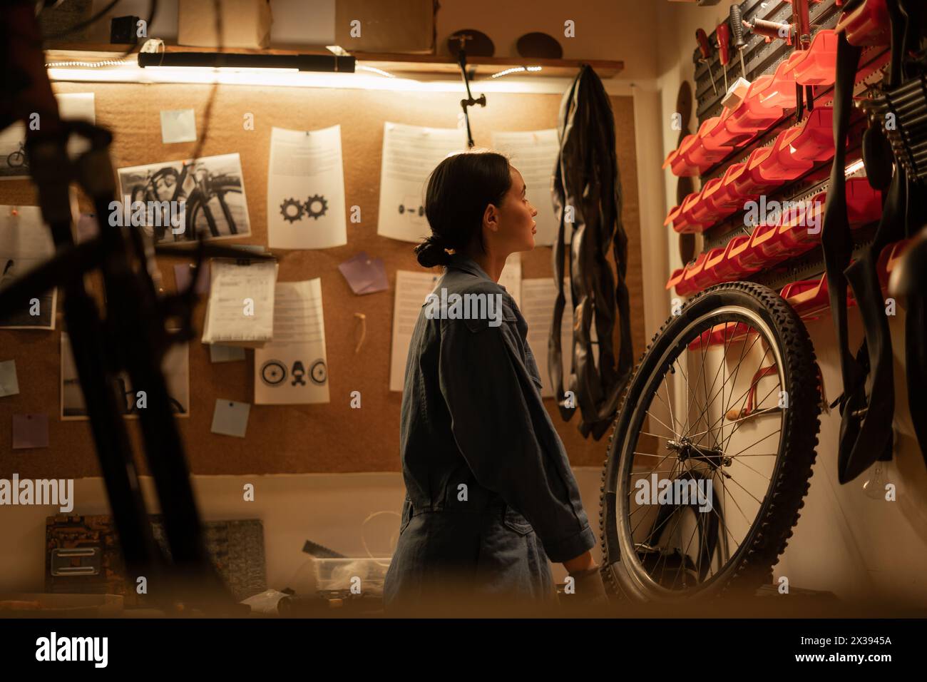 Woman bicycle mechanic standing against wall in garage Stock Photo