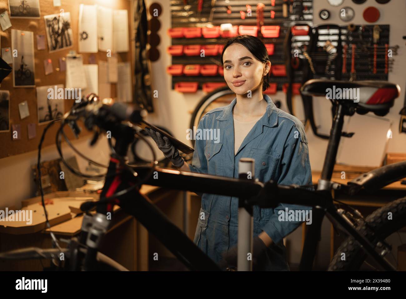 Portrait of Beautiful young female mechanic enjoying while repairing bicycles in a workshop. Stock Photo