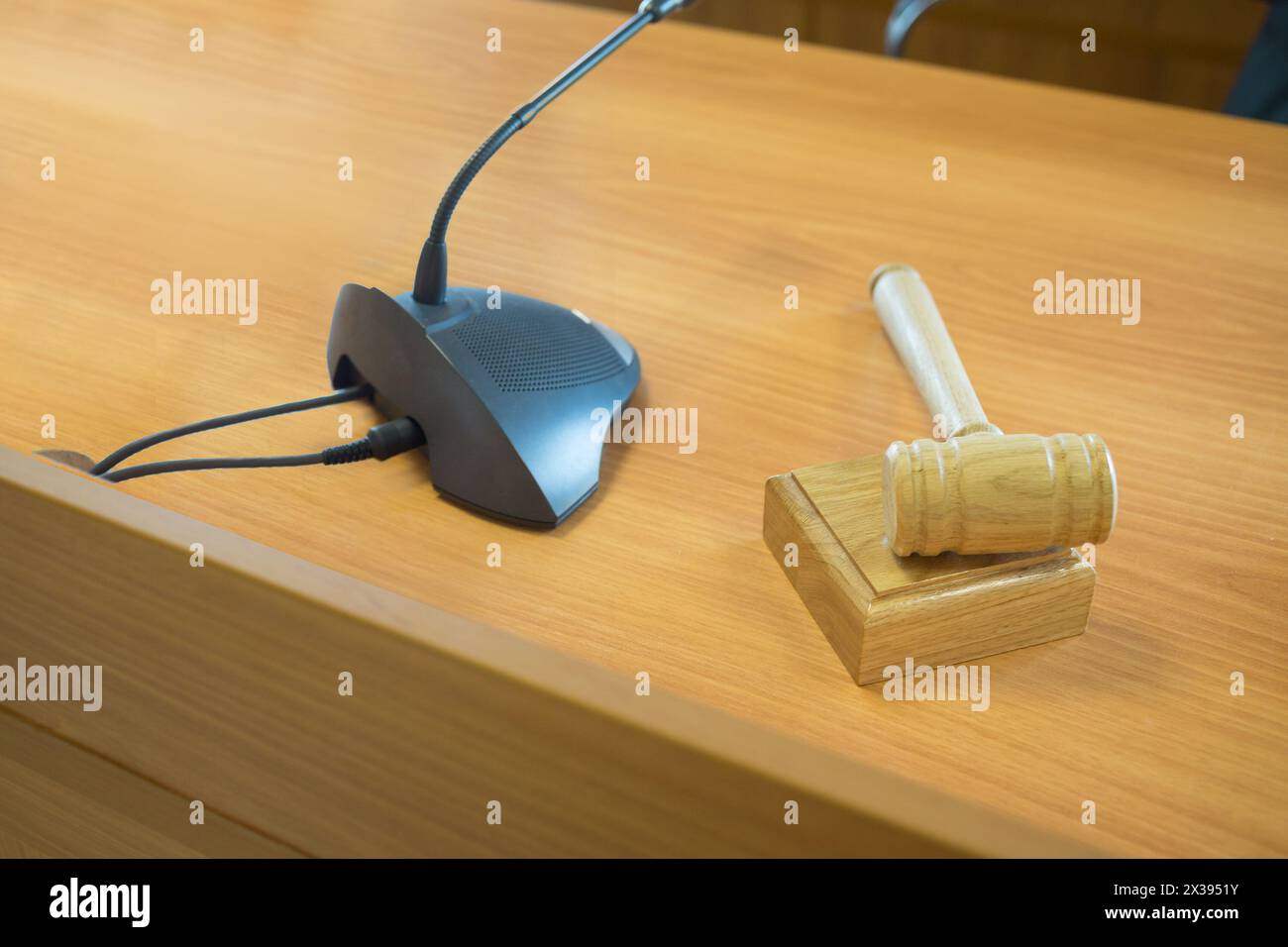 Clean wooden table in court of law with microphone and gavel, focus on gavel. Stock Photo