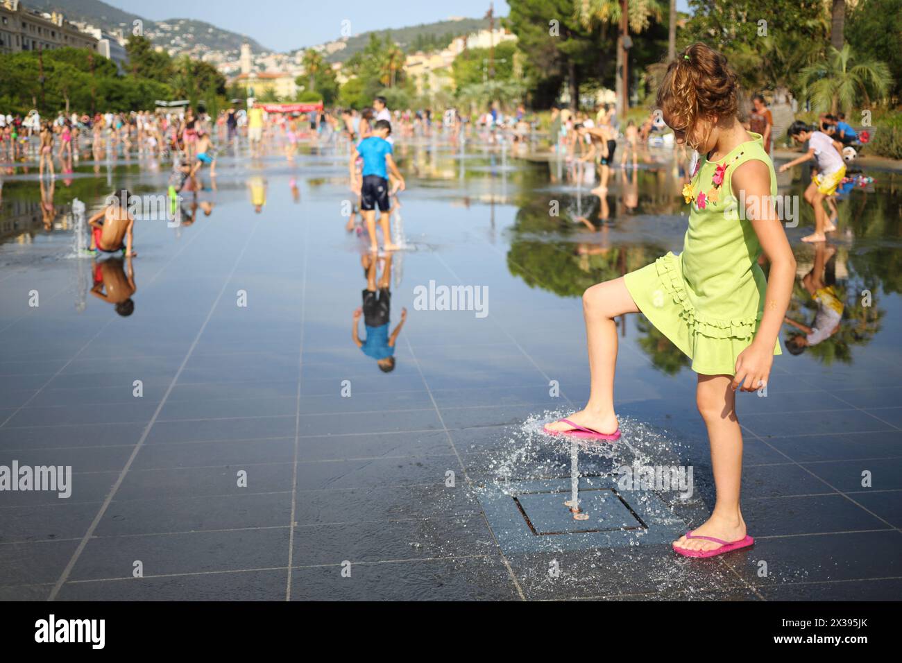 Happy pretty girl plays with dry fountain in summer town, shallow dof Stock Photo
