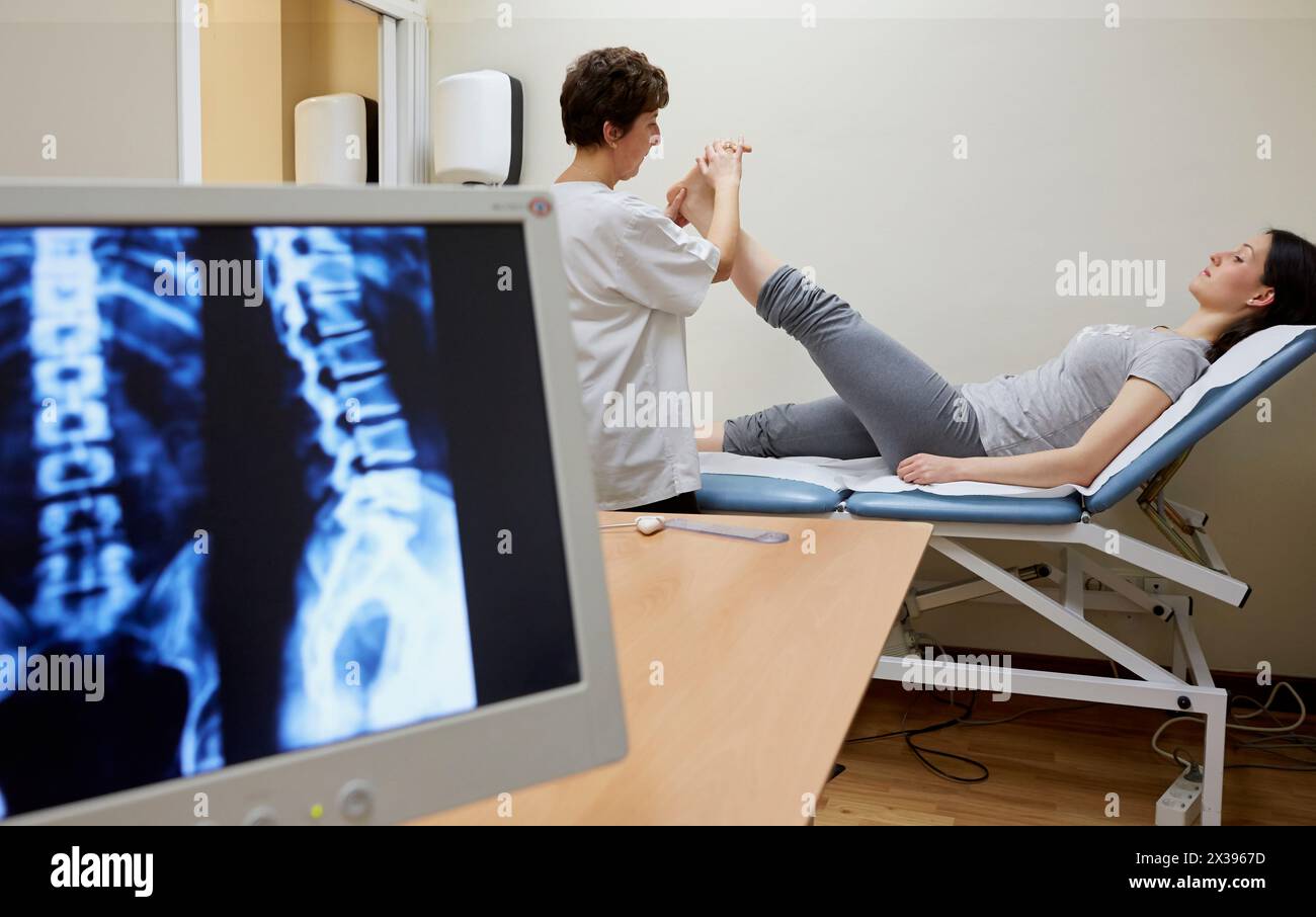 Doctor checking back leg muscle extensibility, Column X-ray image, Physiotherapy medical center, Donostia, San Sebastian, Gipuzkoa, Basque Country, Sp Stock Photo