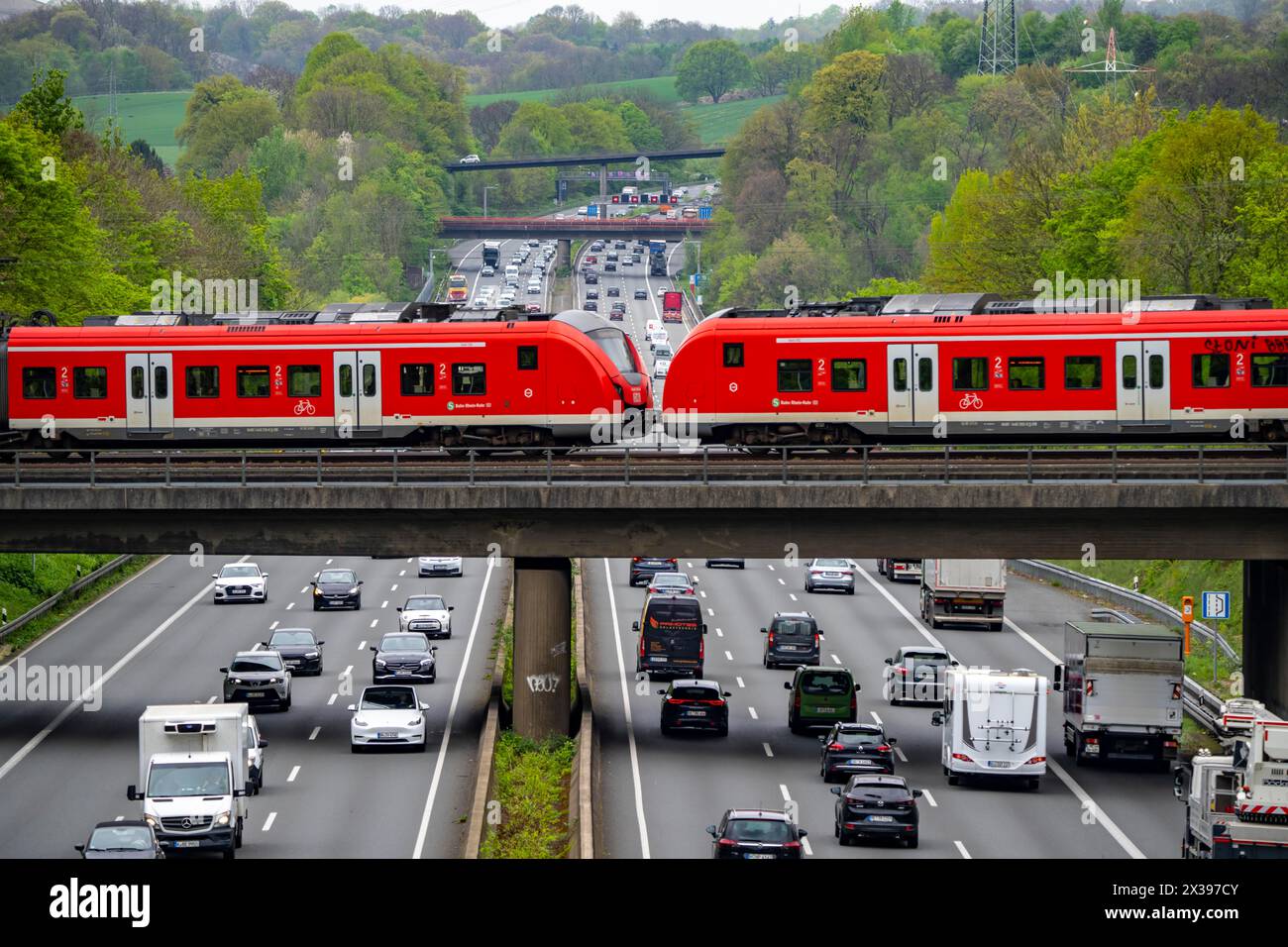 S-Bahn train crossing the highway A3, traffic on 8 lanes, incl. the temporarily released hard shoulder, behind the highway junction Hilden, view in no Stock Photo