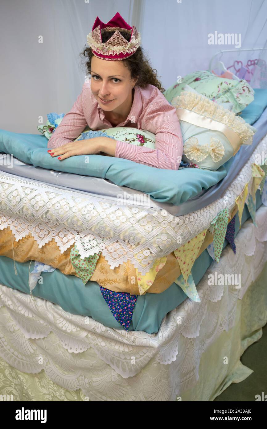 One woman is laying like mollycoddle on the many mattresses under a bed curtain. Stock Photo