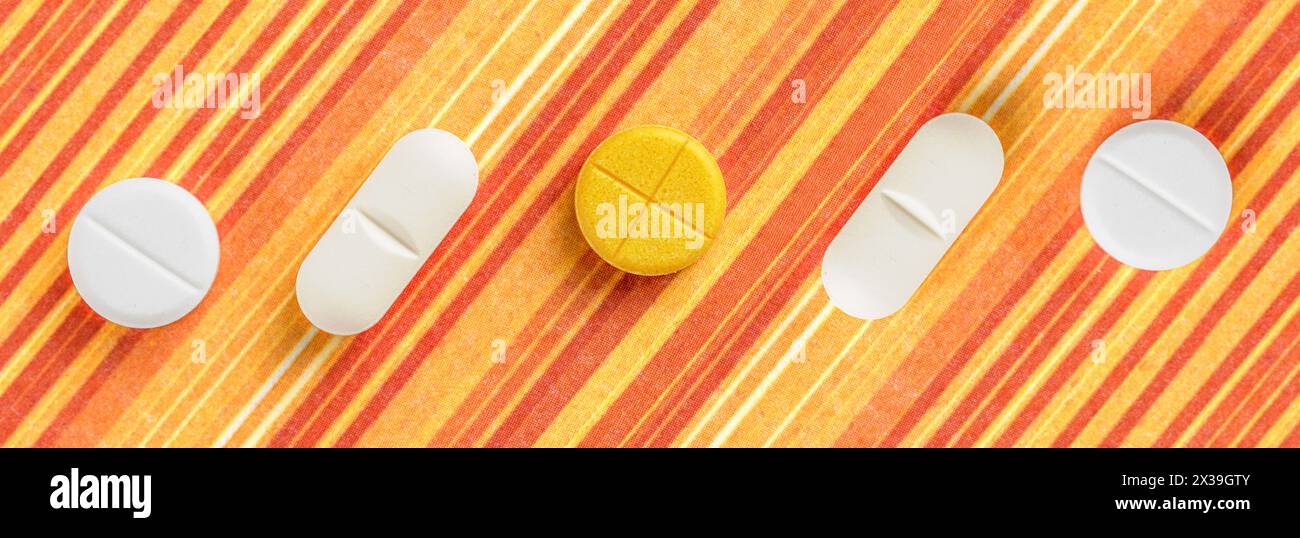Pills and medicines arranged on an orange striped background. It's a visual representation of pharmaceuticals and health-related items. Stock Photo