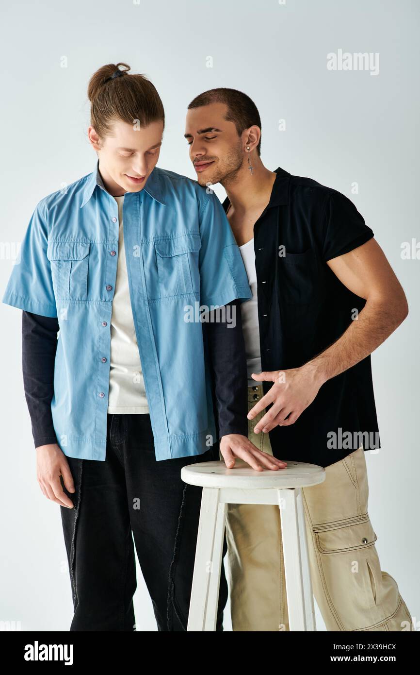 Two men stand near a stool, sharing a moment of closeness. Stock Photo