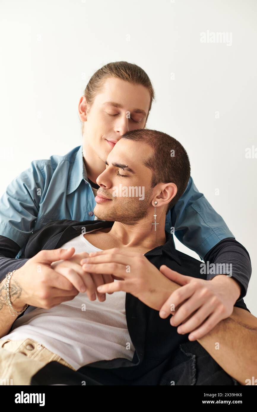 A loving gay couple sitting closely beside each other, sharing a moment of connection and companionship. Stock Photo