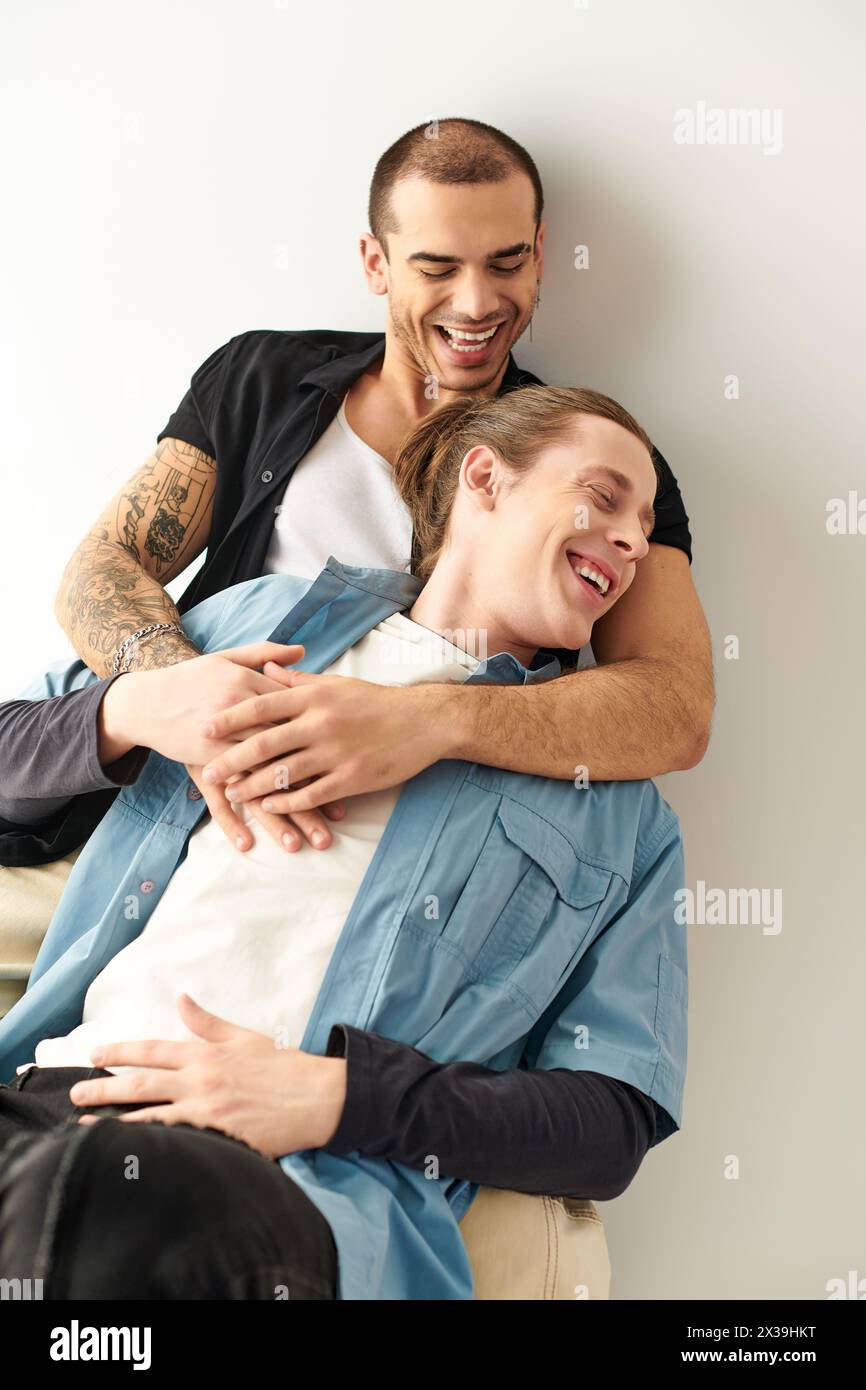 A man lovingly hugs another man on the back of a chair. Stock Photo