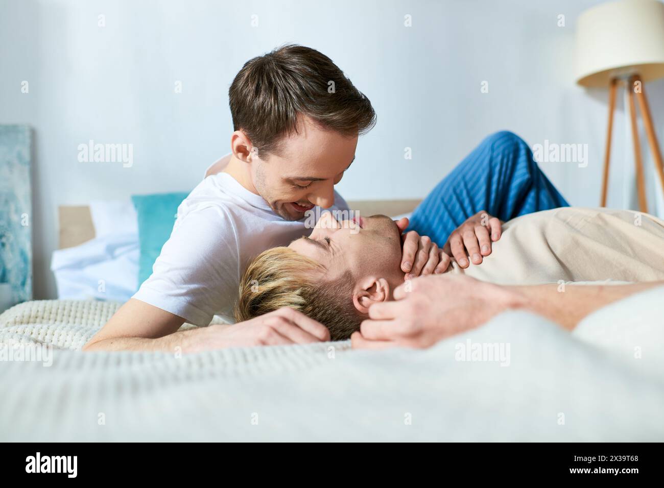 Two men relax on a bed in a cozy setting Stock Photo - Alamy