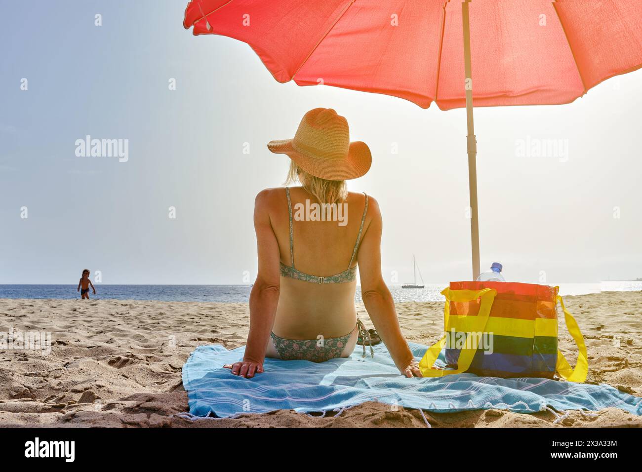 Anonymous woman sitting on blanket on beach Stock Photo
