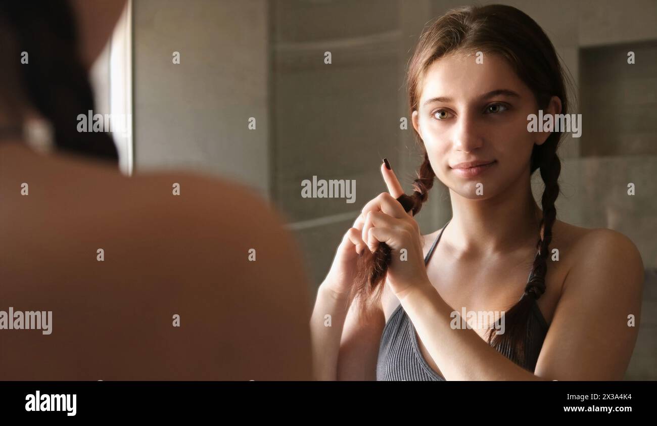 Teenage Girl Brushing And Braiding Her Hair In The Mirror As Part Of ...