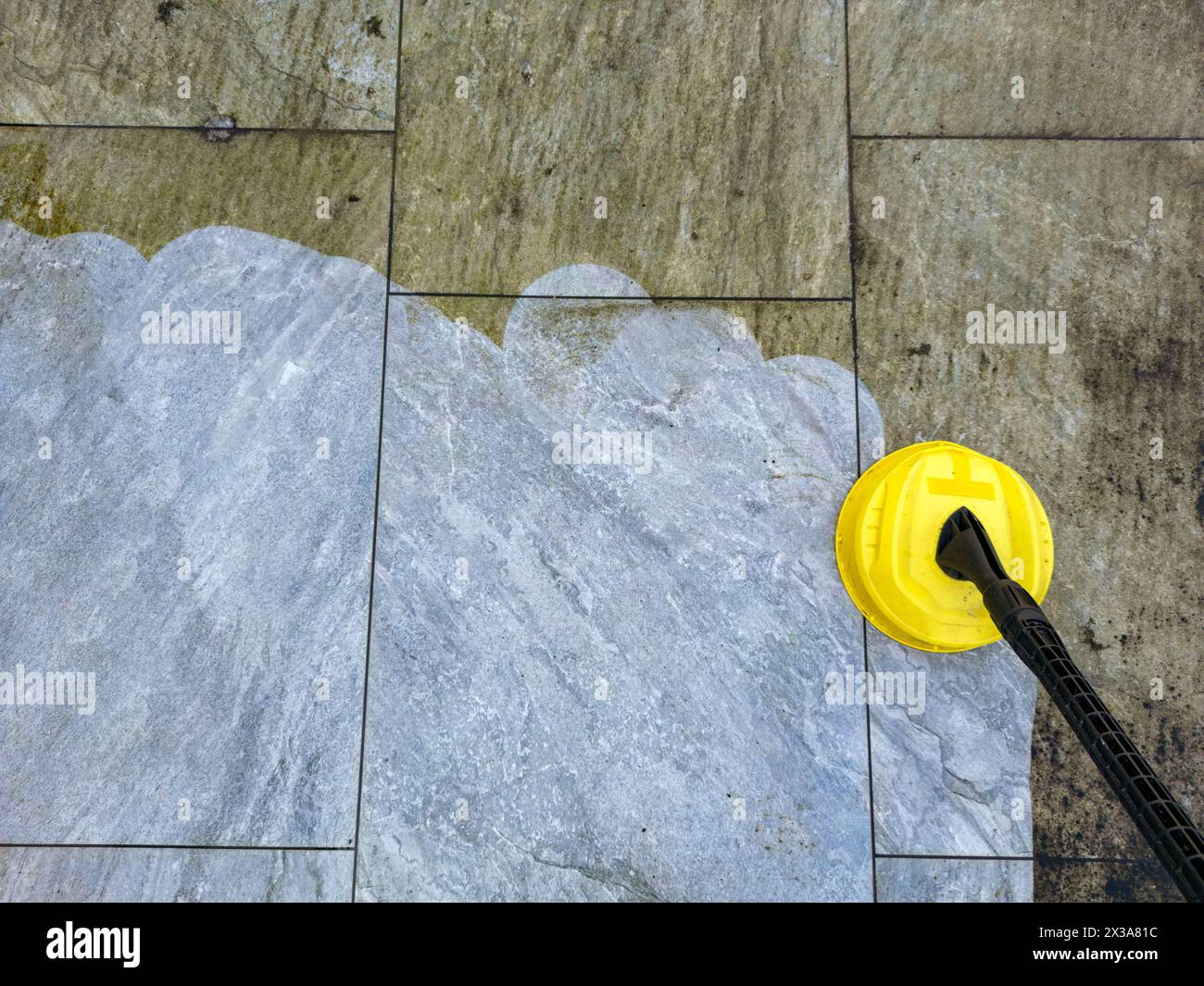 Pressure jet washer being used to clean porcelain tiles on a garden