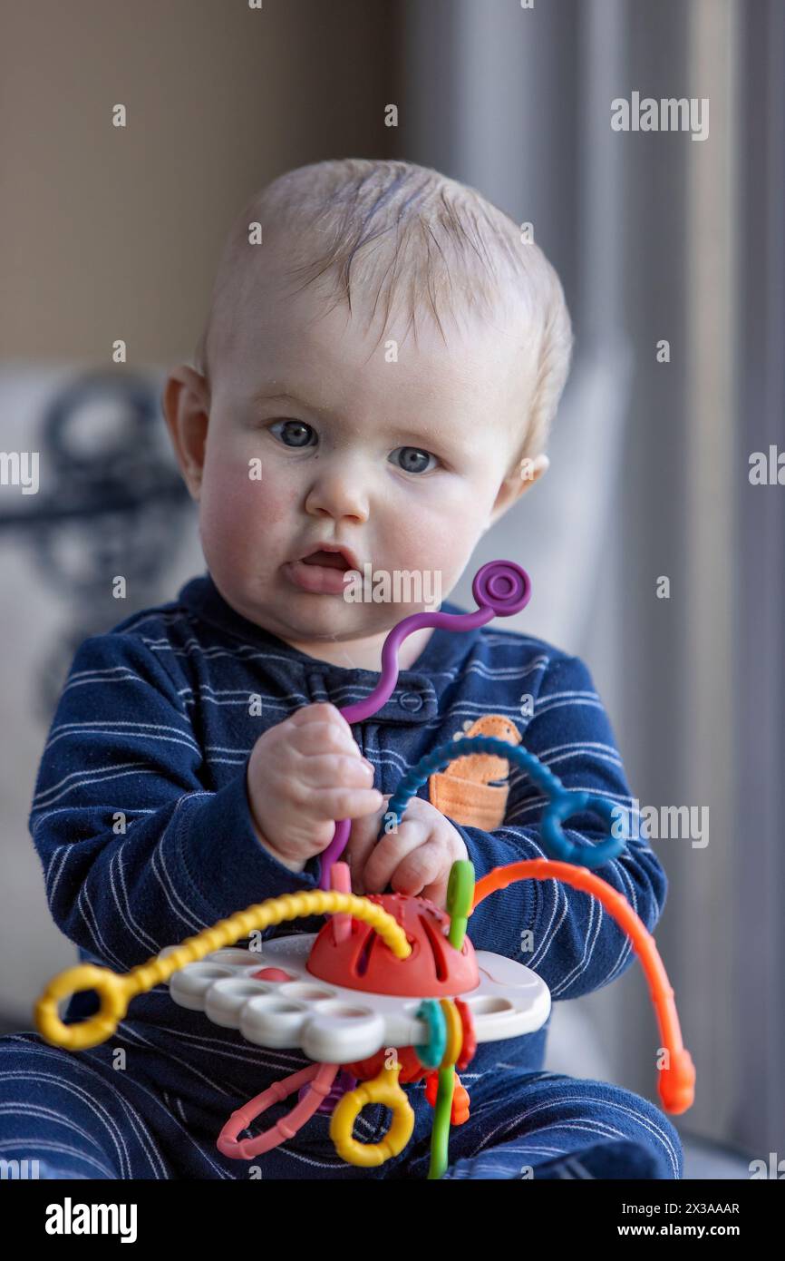 Six month old baby boy sitting and playing with a toy Stock Photo - Alamy