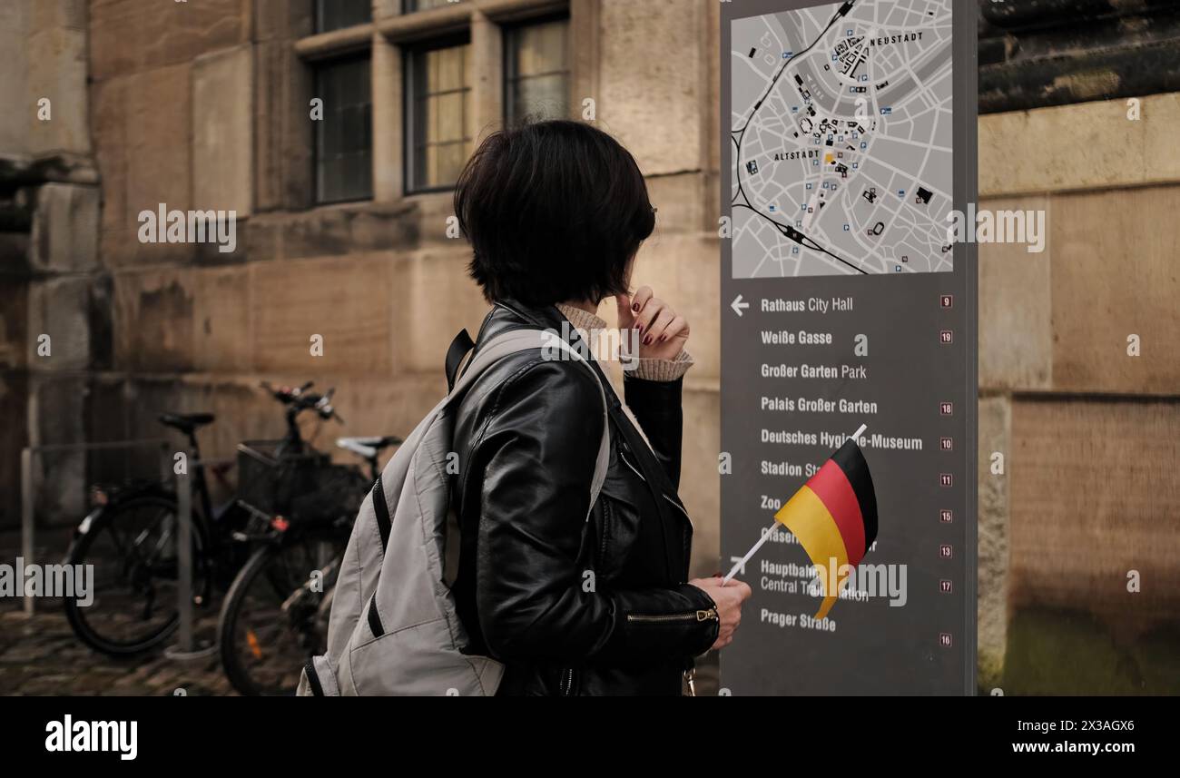 Female history guide walks hi res - Attractive Female Tourist Walks With Germany Flag In Historical Center Of Dresden Checking Touristic Route On City Map 2X3AGX6
