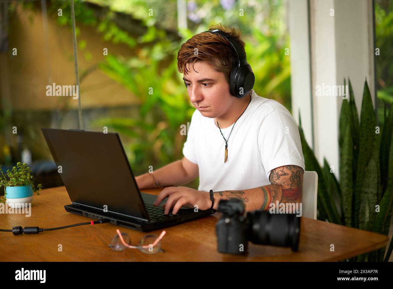 Trans Guy Computer Llockscreen Transgender editor with tattoos works on laptop in green office ...