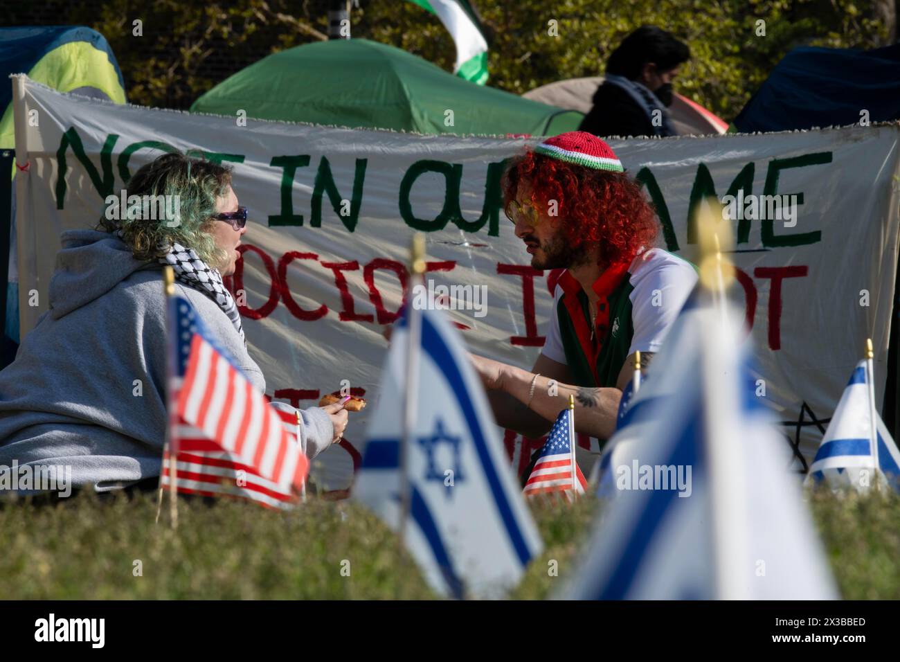 Ann Arbor, Michigan, USA. 25th Apr, 2024. Two protesters eat pizza at the encampment on the Quad at the University of Michigan in Ann Arbor. Israeli and America flags were placed right next to the encampment. (Credit Image: © Mark Bialek/ZUMA Press Wire) EDITORIAL USAGE ONLY! Not for Commercial USAGE! Stock Photo