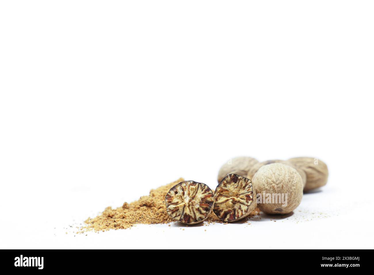 Whole nutmeg, halved and ground, on a wooden spoon isolated on a white background and copy space Stock Photo