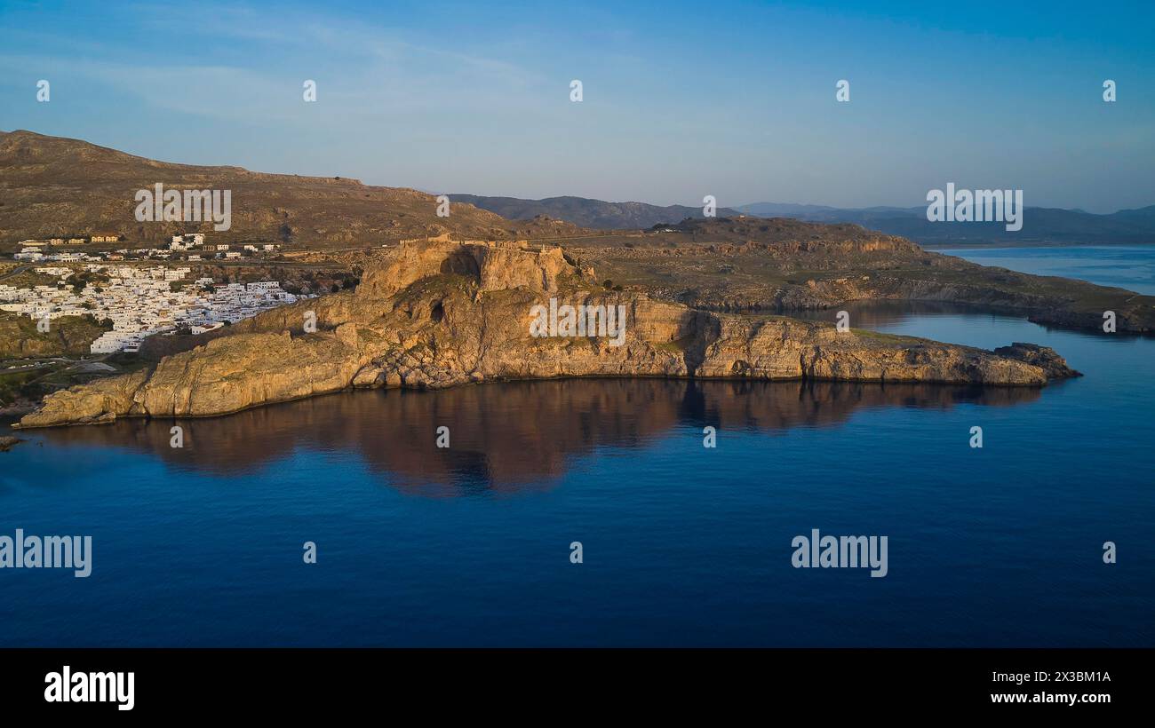 Drone shot, first morning light, Lindos, Acropolis of Lindos, Wide view of steep coast and sea under a wide, peaceful evening sky, Archaeological site Stock Photo