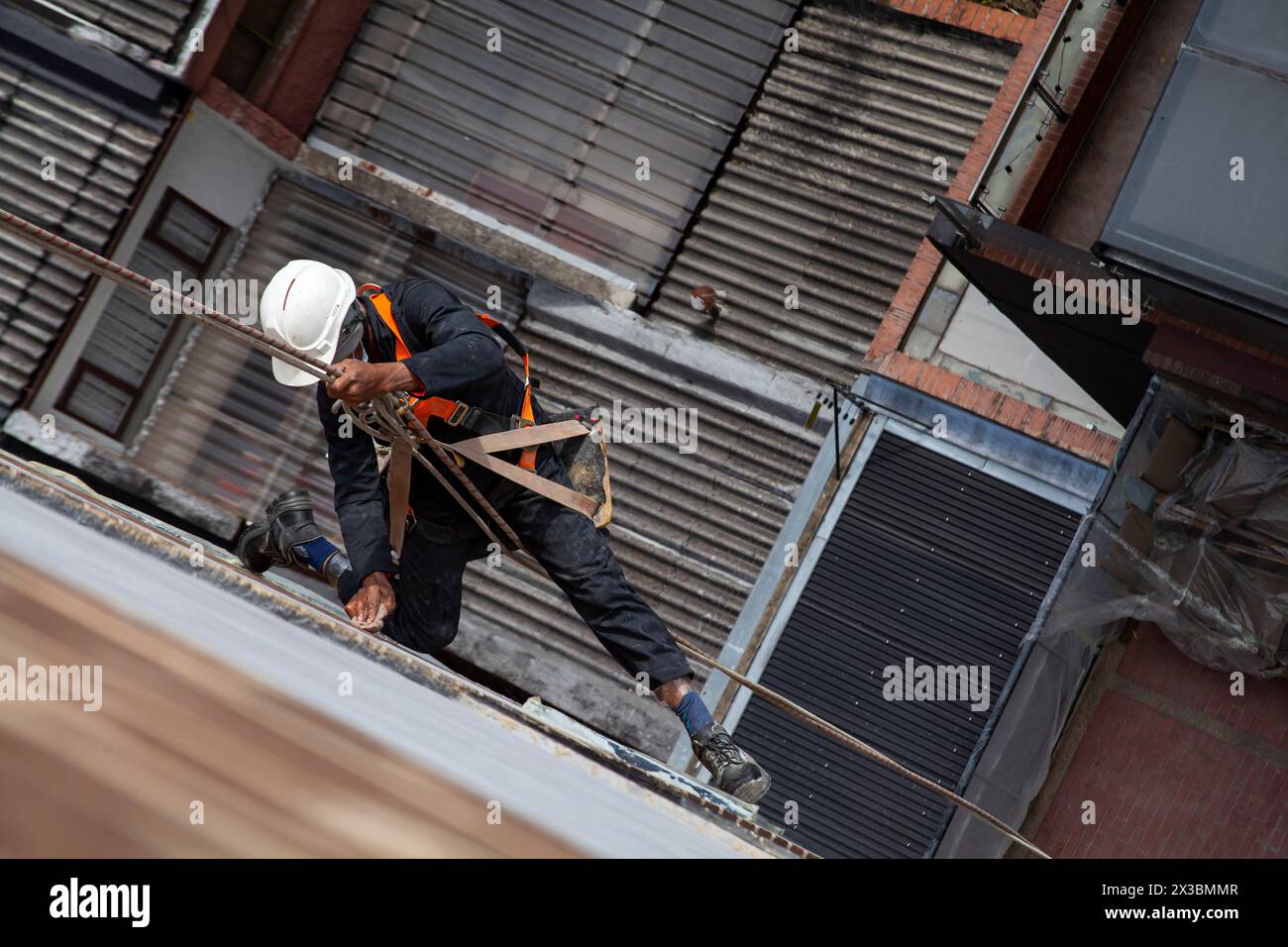 rope secured worker hangs from the building Stock Photo