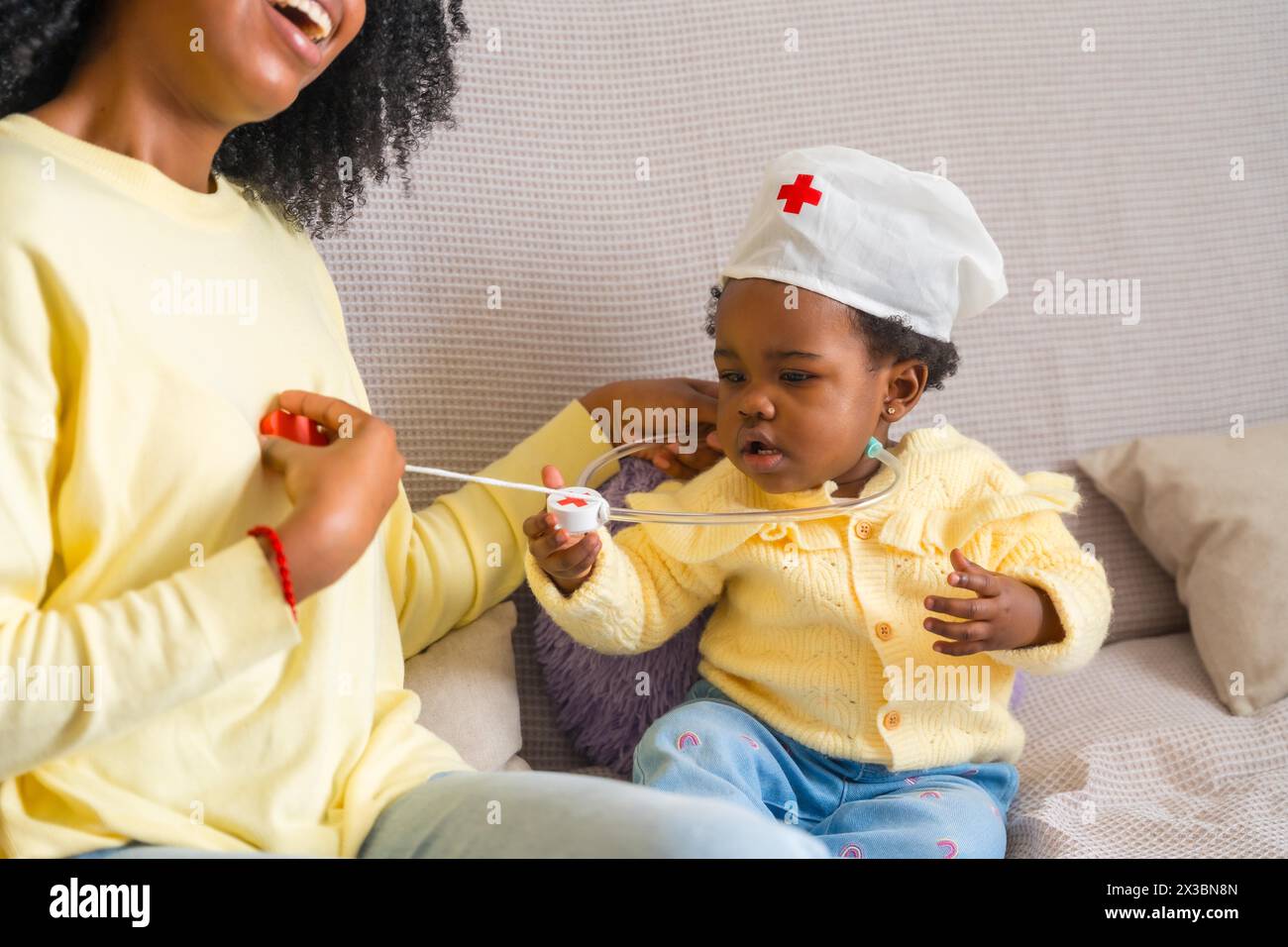Domestic scene of a cute african nurse playing with her mother on the sofa Stock Photo