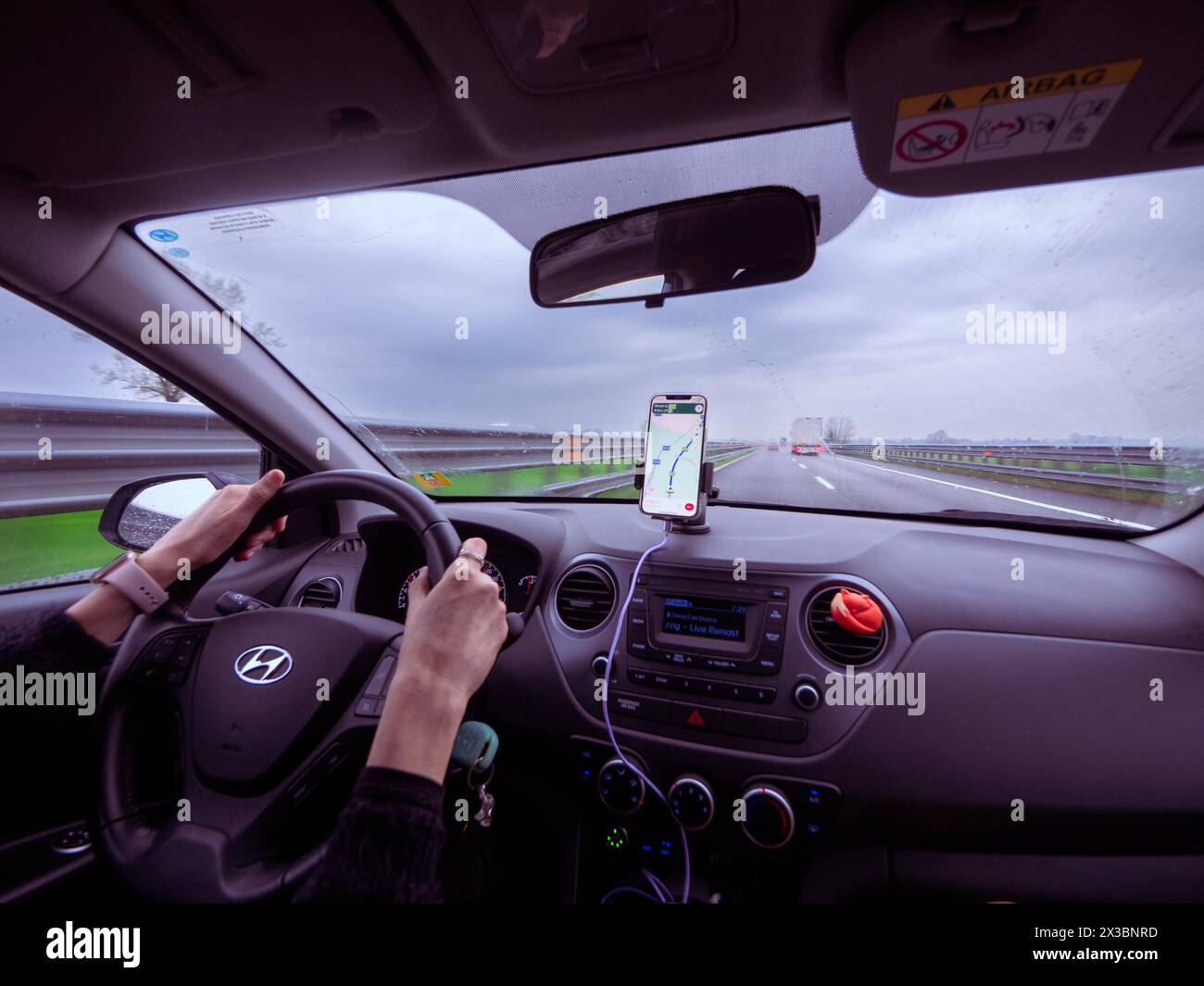 Driver's view from inside a car with a phone showing navigation on a ...