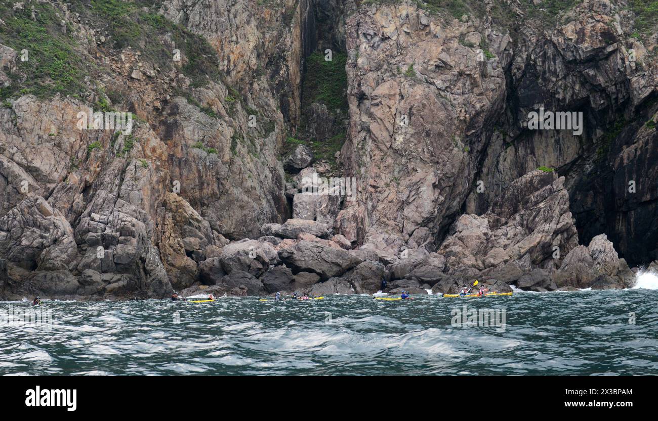 Kayaking by the rugged coastal landscapes in Sai Kung East Country park in Hong Kong. Stock Photo