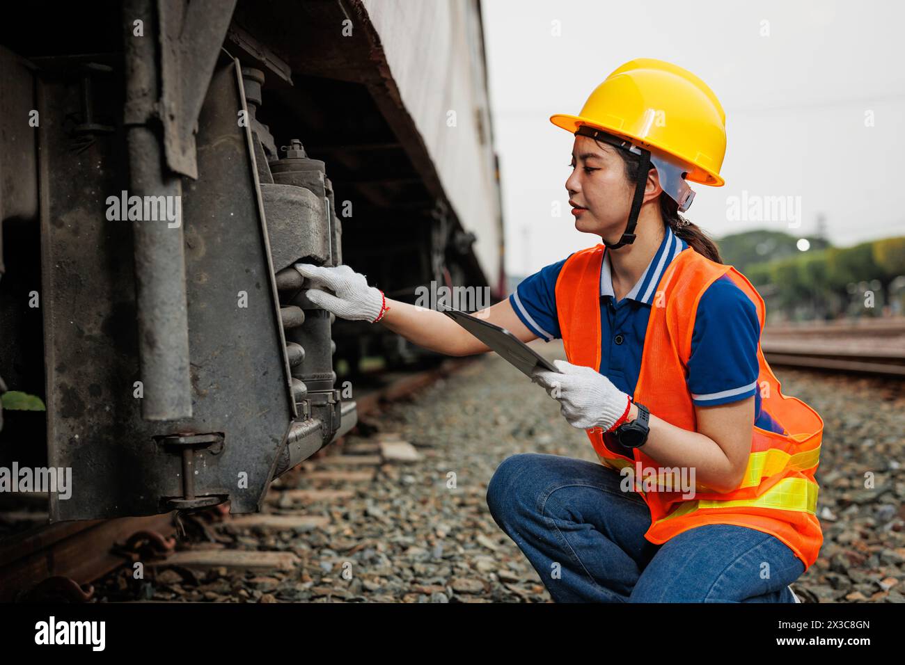 Train locomotive engineer women worker. Young teen Asian working check service maintenance train using tablet computer software. Stock Photo