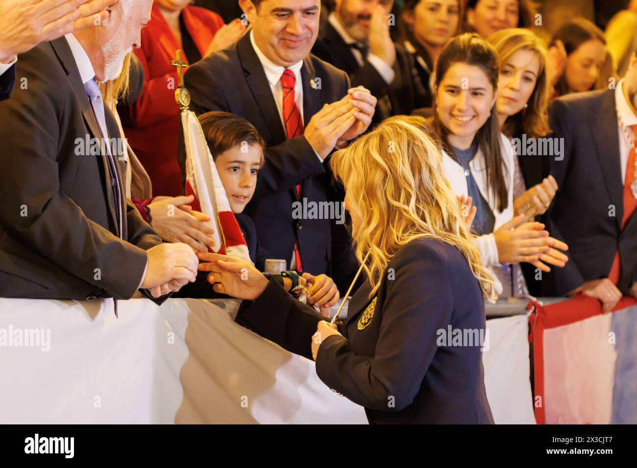 Alcoy, Spain, 04-19-2024: Director of the Alcoy festival anthem Blanca Carbonell receiving the baton from the child who will represent Saint George in Stock Photo