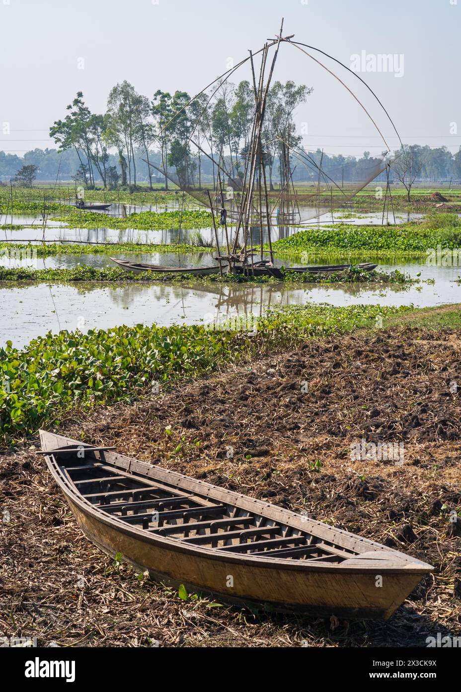 Vertical rural landscape with wooden boats and chinese fishing net in Tangail countryside, Bangladesh Stock Photo