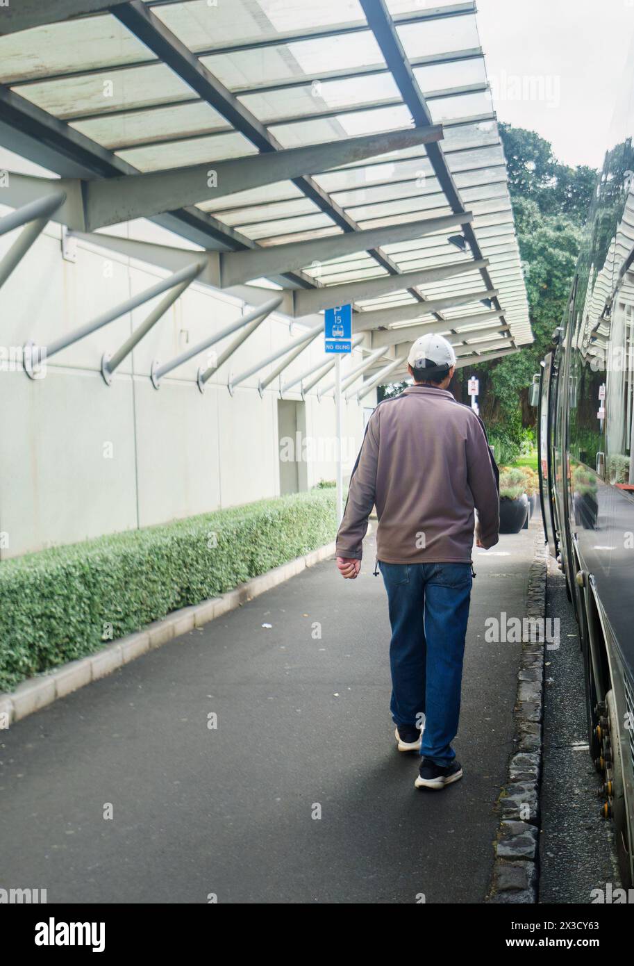 Man walking to the bus stop on an overcast day. Vertical format. Stock Photo