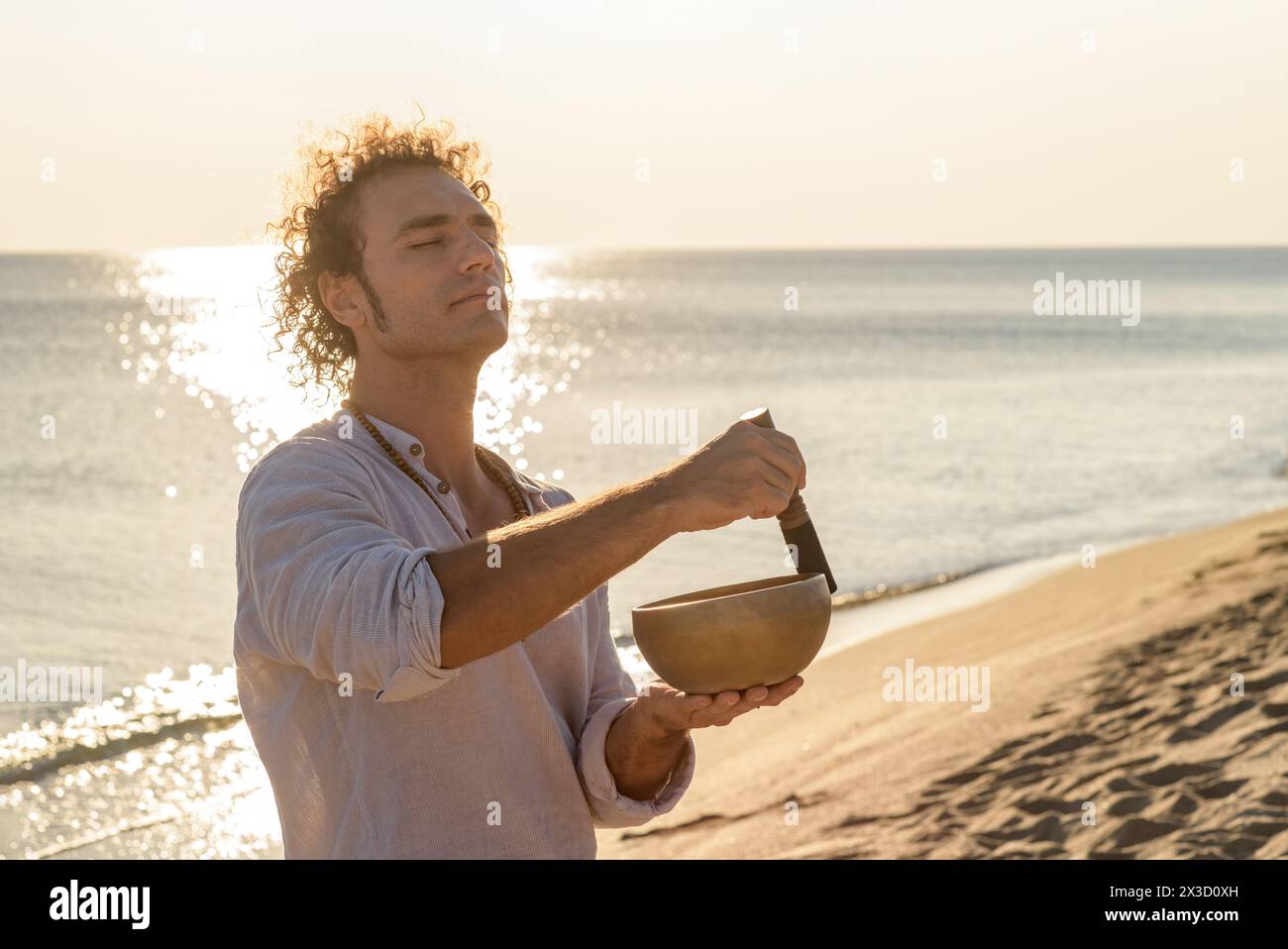 Man meditating with a singing tibetian bowl on the sea Stock Photo