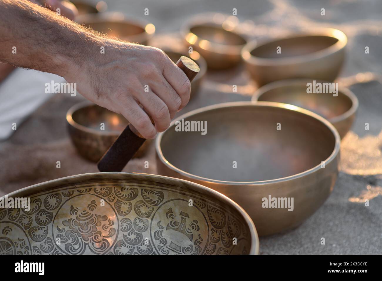 Man’s hands playing on a singing tibetian bowl with sticks Stock Photo