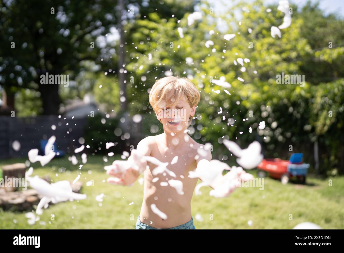 Boy playing with foam bubbles in backyard Stock Photo