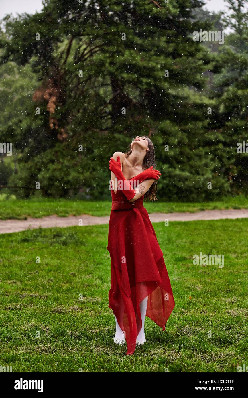 An enchanting young woman in a vibrant red dress gracefully stands in ...