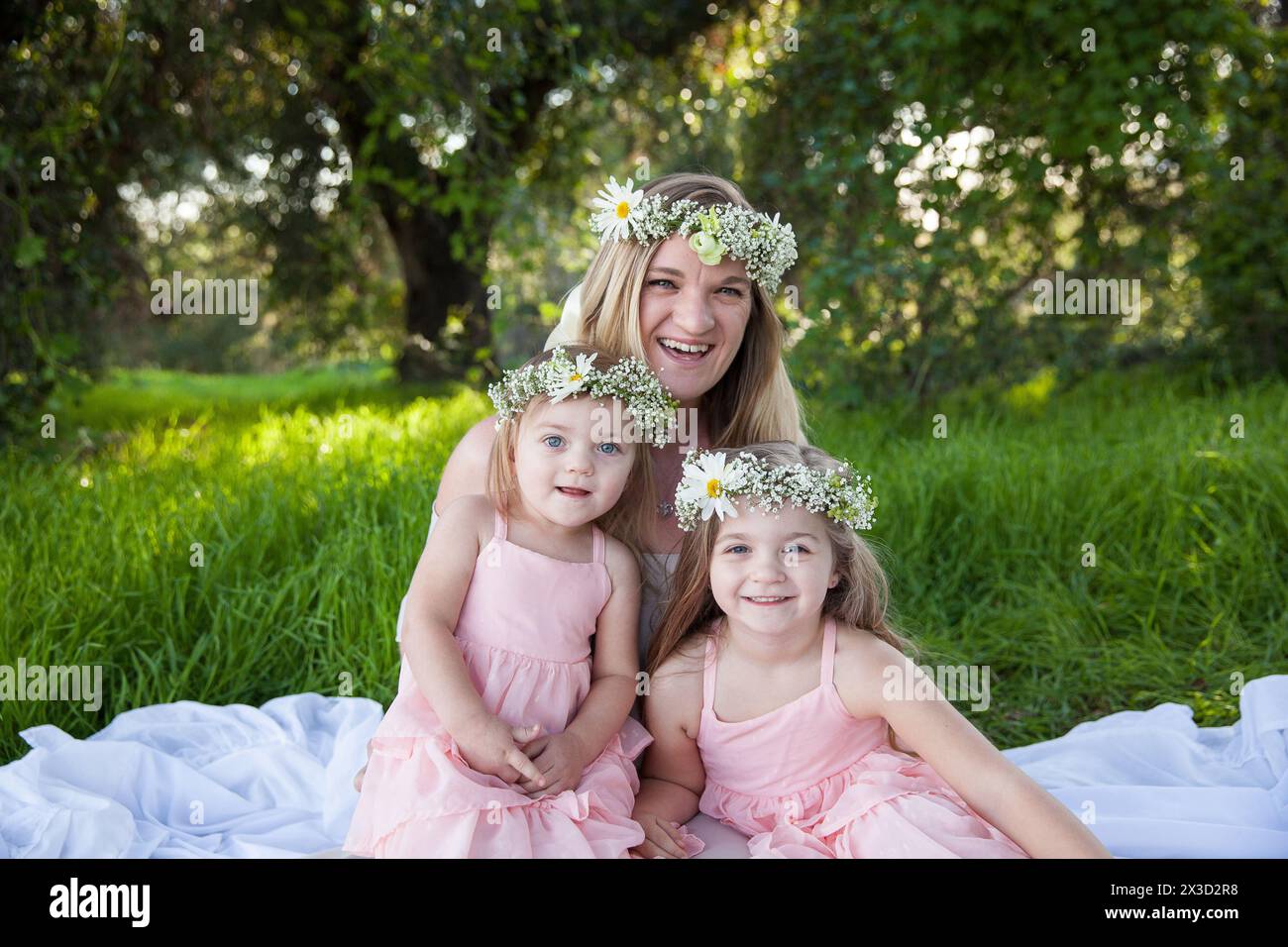 Joyful family moment with flower crowns in sunlit meadow Stock Photo