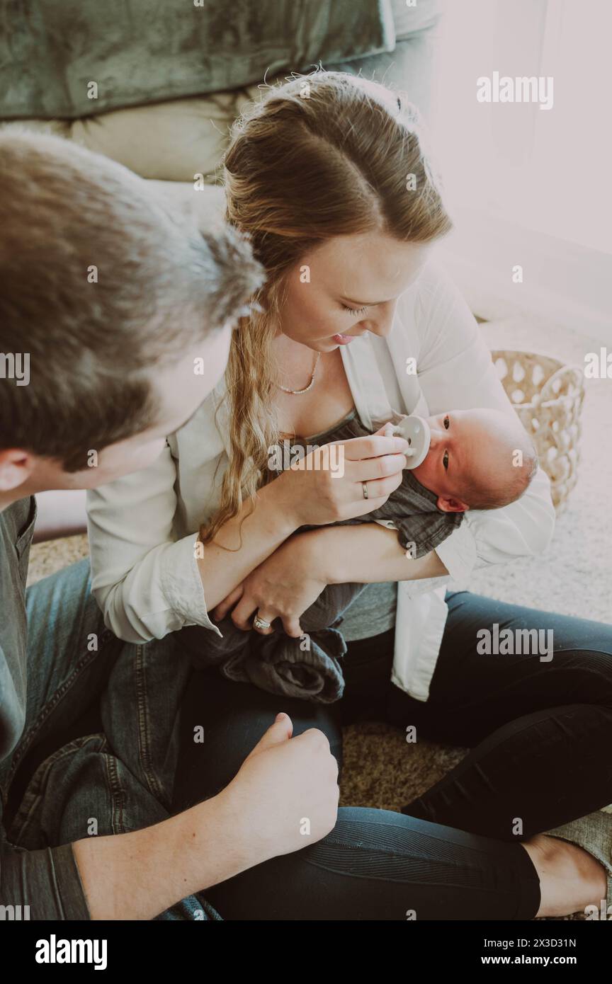 Mom and dad looking at new born baby cradled in moms arms Stock Photo ...
