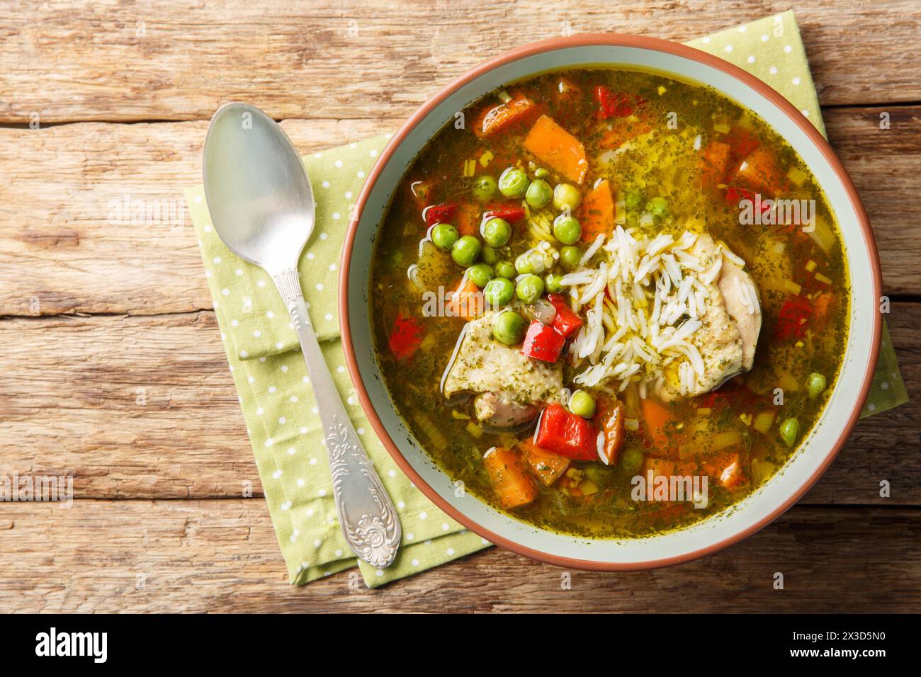 Aguadito de Pollo is a Peruvian cuisine, combining ingredients such as chicken, rice, vegetables and coriander in a tasty broth closeup on the bowl on Stock Photo