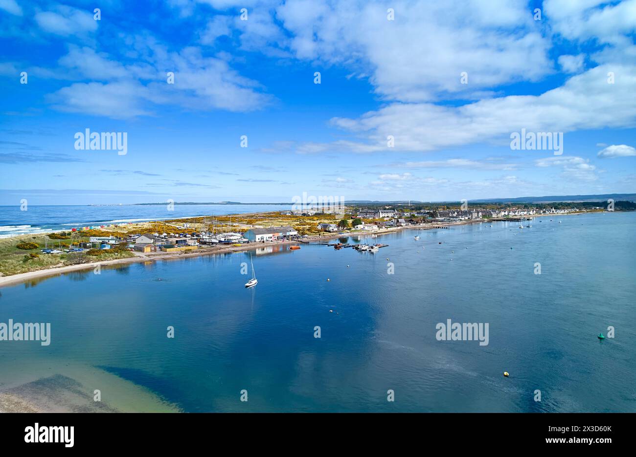 Findhorn Moray Coast Scotland blue sky in Springtime over the gorse covered peninsula and calm sea of the bay at high tide Stock Photo