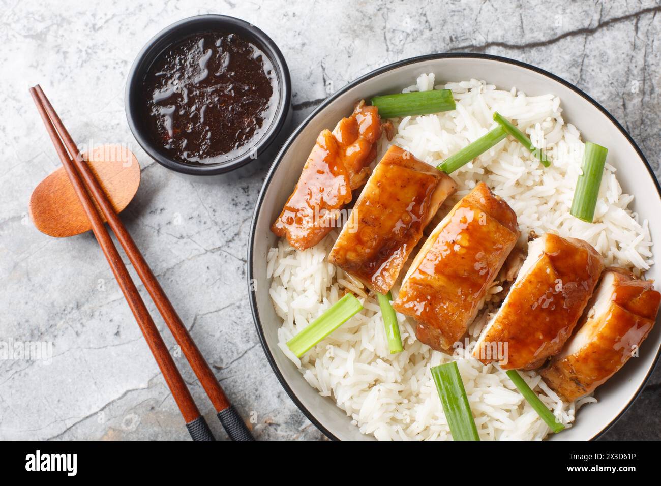 Homemade soy sauce chicken has silky tender meat with a deep savory flavor served with rice and dipping sauce closeup on the table. Horizontal top vie Stock Photo