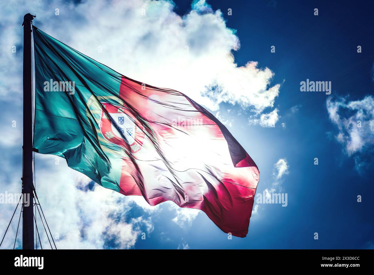 The vibrant colors of the Portuguese flag ripple in the breeze, proudly displayed against a striking backdrop of a clear blue sky Stock Photo