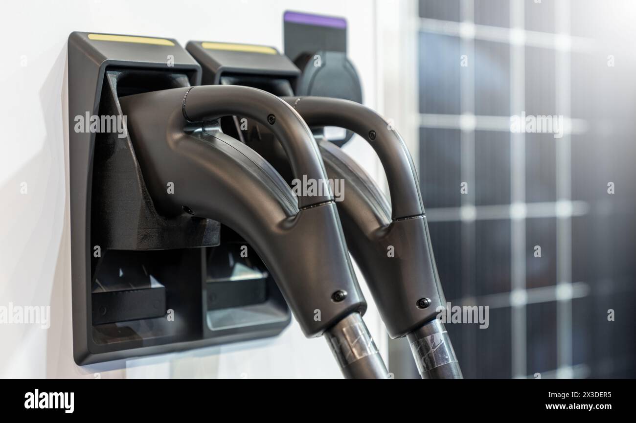 Close up of electric car charging station on the background of solar panels. Stock Photo