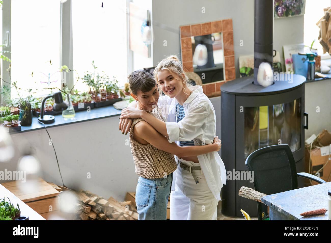 Two women, a loving lesbian couple, standing together in an art studio. Stock Photo