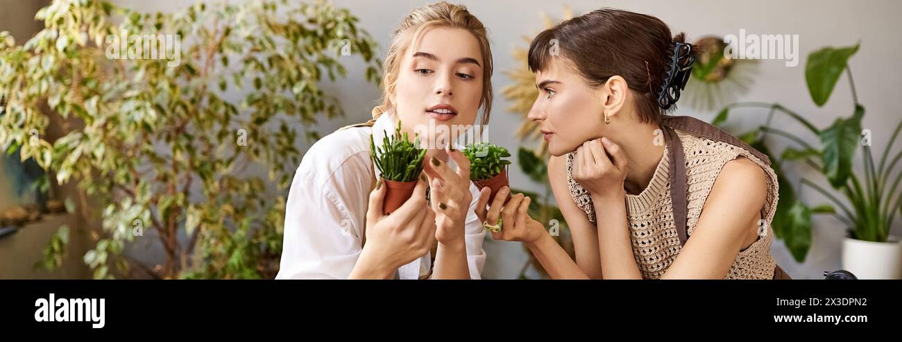 Lesbian couple enjoying art studio, holding plants, surrounded by creativity. Stock Photo