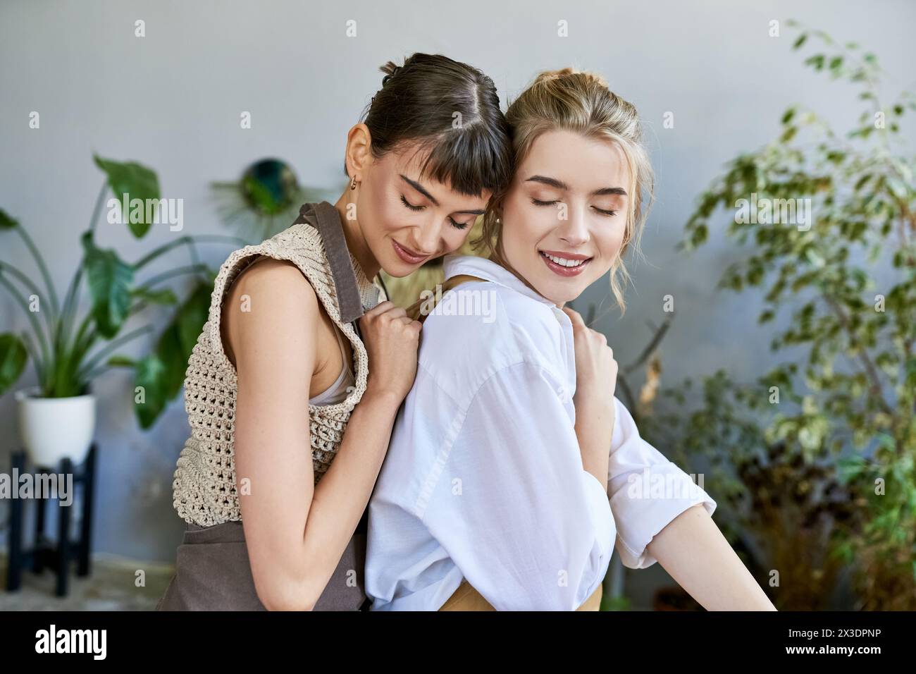 Two women sharing a heartfelt hug in an art-filled space. Stock Photo