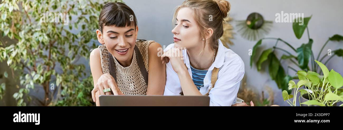 Two young women, immersed in the glow of a laptop screen at an art studio. Stock Photo