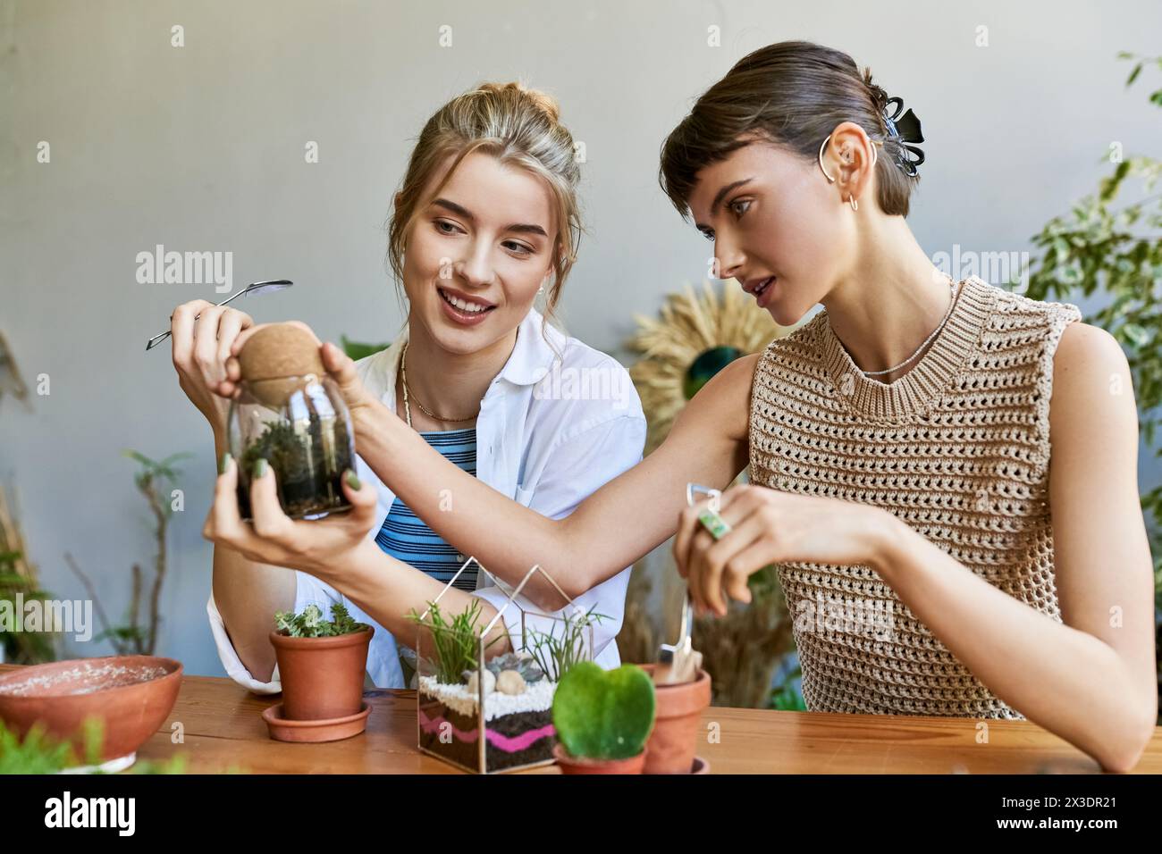 Two women admiring a potted plant together in an art studio. Stock Photo