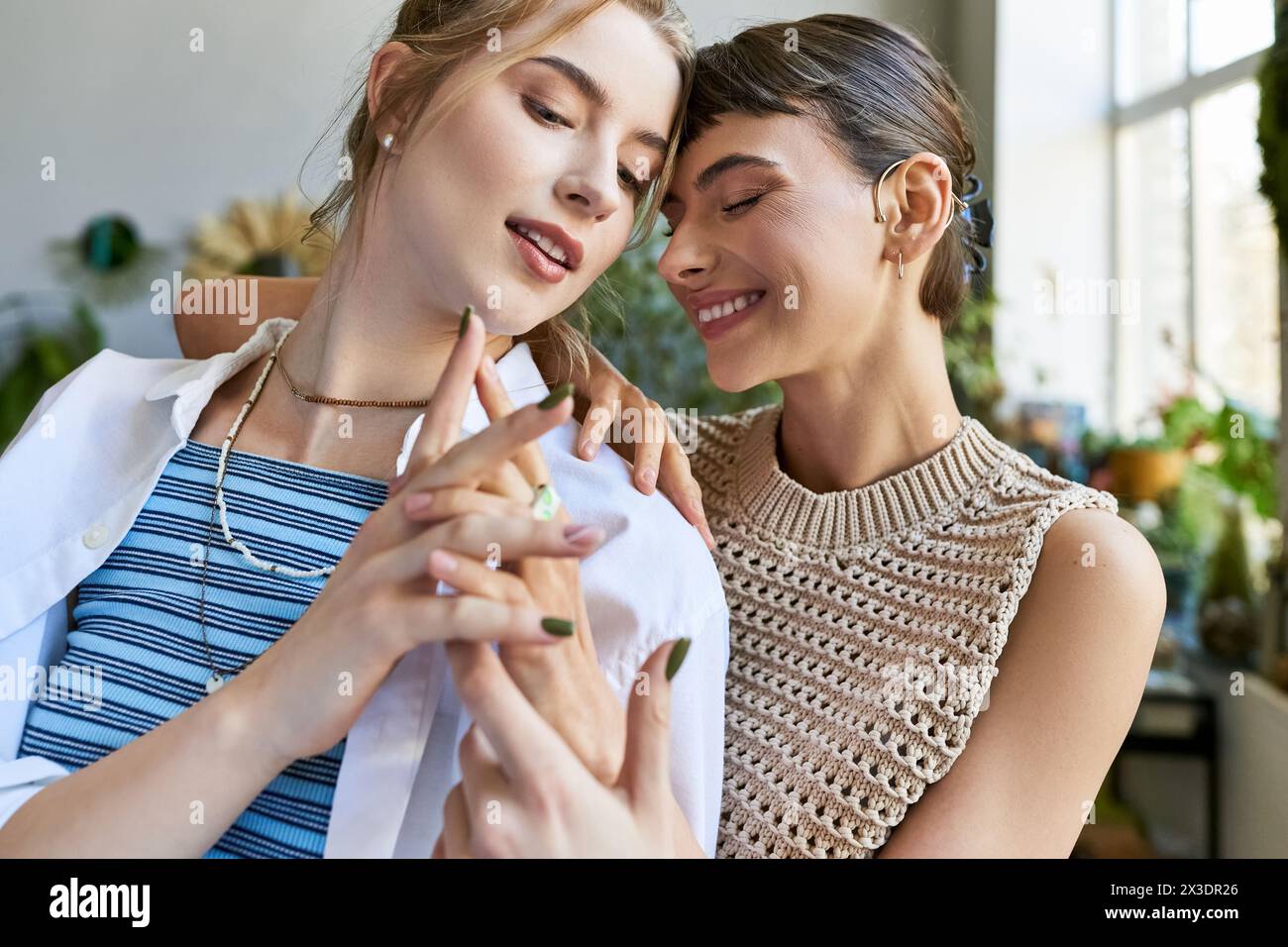 A loving lesbian couple, both women, stand together at an art studio, deep in thought. Stock Photo
