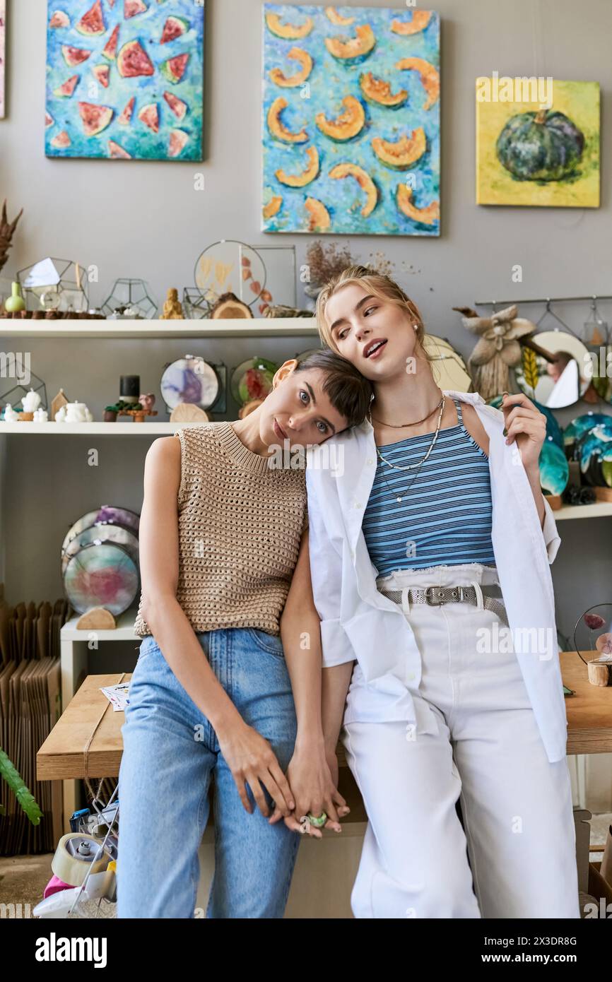 A loving lesbian couple sitting on a bench in an art studio. Stock Photo