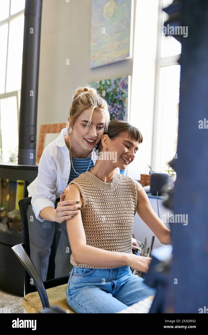 Two women embrace on a chair in an art studio. Stock Photo