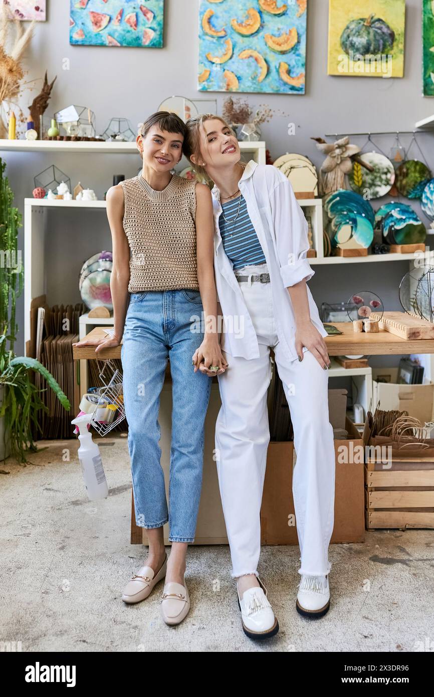 Two women, a romantic lesbian couple, standing together in an art studio. Stock Photo
