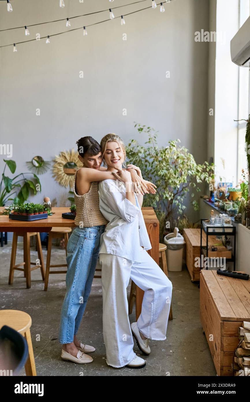 Two women standing side by side in an art studio, sharing a tender moment. Stock Photo